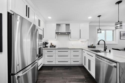 a kitchen with white cabinets and a stainless steel refrigerator at Modern Escape - Luxe Oceanfront 2BR with Epic Kitchen, Pool, Parking in Myrtle Beach