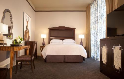 a hotel room with a bed and a table and a desk at The Ashton Hotel in Fort Worth