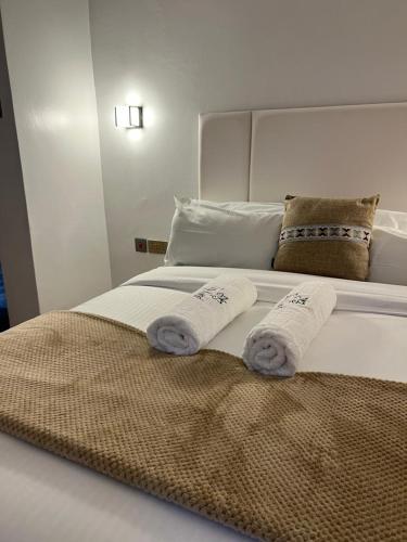 a white bed with two towels on top of it at Tiny Card Milimani Homes in Kisumu