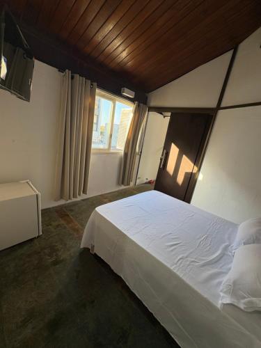 a bedroom with a white bed and a window at Pé na areia 5 in Torres