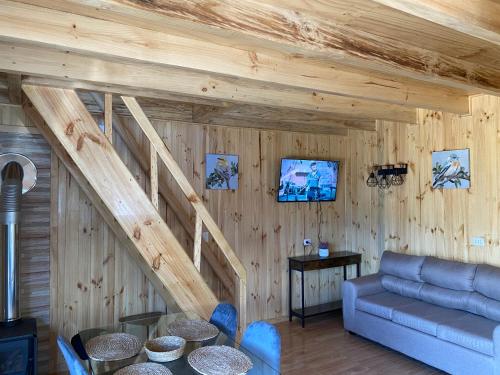 un soggiorno con divano blu e pareti in legno di Cabañas alto de coñaripe a Coñaripe