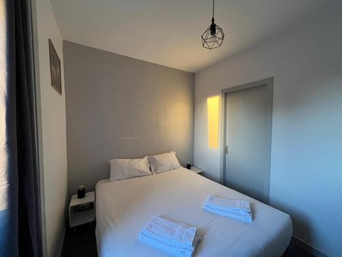 una camera da letto con un letto bianco con due asciugamani sopra di Brit Hotel L'Arrivée Guingamp a Guingamp