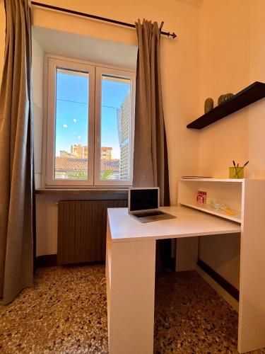 a white desk with a laptop on it in front of a window at Fandara Suites in Turin