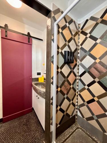 a bathroom with a red door and a checkered wall at Fandara Suites in Turin