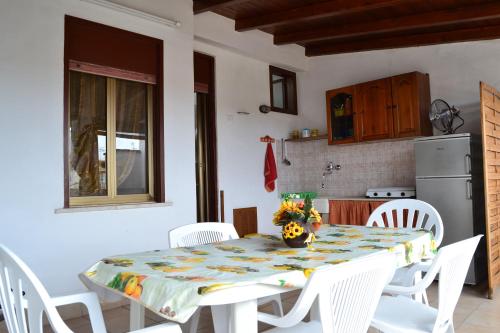 a kitchen with a table and white chairs at Casa Vacanze Laura in Isola delle Femmine