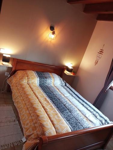 a bed in a room with two lights on the wall at La Cabane du Berger & son terrain de pétanque in Torsiac