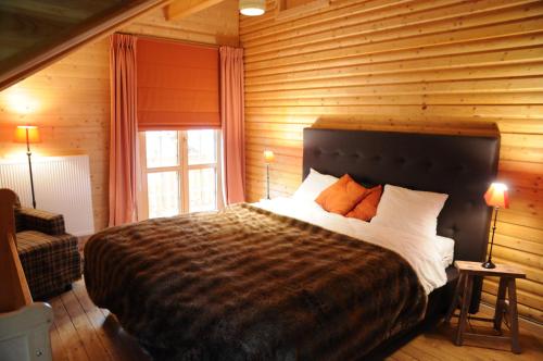 een slaapkamer met een groot bed in een houten muur bij La Grande Ourse in Durbuy