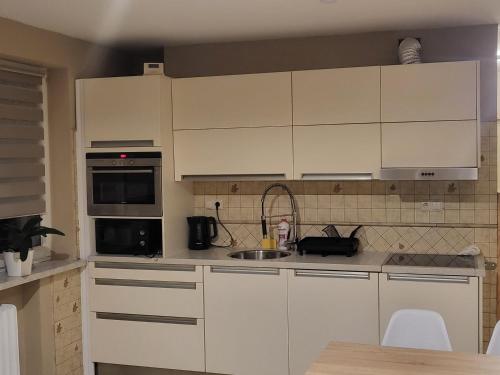 une cuisine avec des armoires blanches et un évier dans l'établissement Apartament Bajka, à Bolesławiec