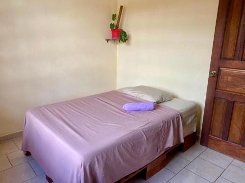 een klein bed in een kamer met een paarse deken bij Casa Ocho in Jacó