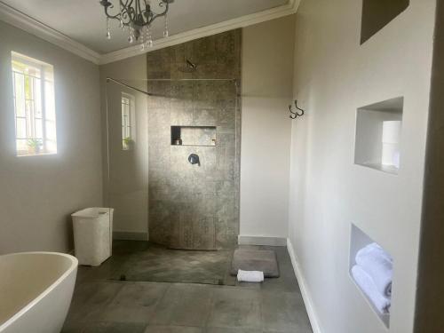 un bagno con doccia, vasca e lavandino di The Townhouse Mkhondo a Piet Retief
