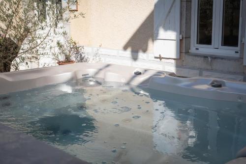 een bad gevuld met water naast een gebouw bij La Maison du soleil L Aulhere 3 étoiles ,Maison familiale 6-7 personnes, Grand Jacuzzi 6 p in Oloron-Sainte-Marie