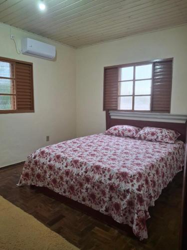 a bedroom with a bed and two windows at Casa Hermosa in São Gabriel