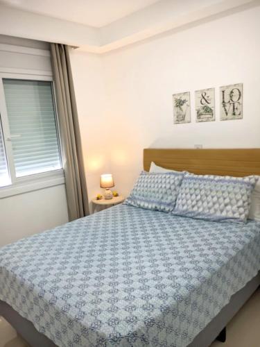 a bedroom with a bed with a blue comforter and a window at Buenos Aires 605 in Osório
