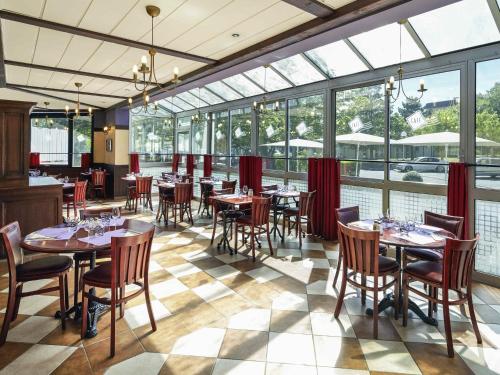 a dining room with tables and chairs and windows at ibis Chartres Ouest Luce in Chartres