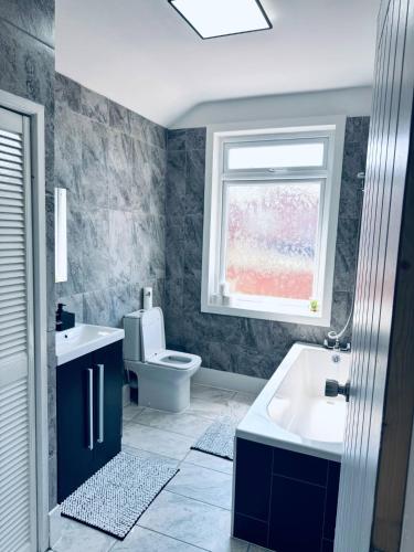 a bathroom with a sink and a toilet and a window at Sterling House - by Eazystays in Crewe
