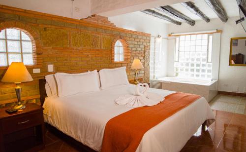 a bedroom with a bed with a bow on it at Hotel Los Frayles in Villa de Leyva