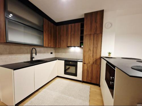 een keuken met witte kasten en zwarte aanrechtbladen bij Infinity Apartment & Privat Garage in Sarajevo