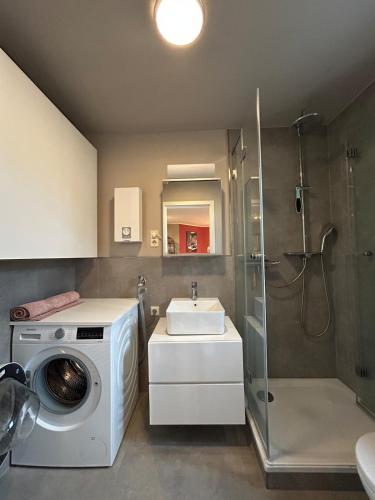 a bathroom with a washing machine and a sink at Helle Souterrain-Wohnung mit eigenem Eingang in Erftstadt