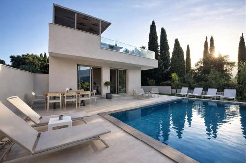 a house with a swimming pool and a table and chairs at Villa Harmony Luxury Resort in Corfu