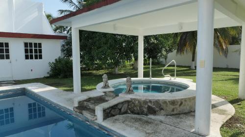 a swimming pool with a fountain in a house at Alojamiento con alberca privada y jardín grande in Tecolutla
