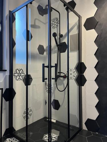 a shower in a bathroom with black and white tiles at A-frame Boema in Cîmpu lui Neag