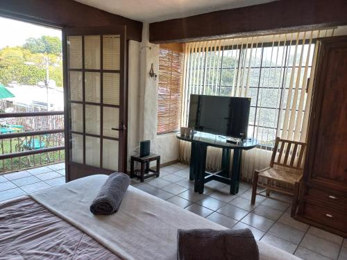 a room with a bed and a television and a table at La Casa del Sol - Cuernavaca in Cuernavaca