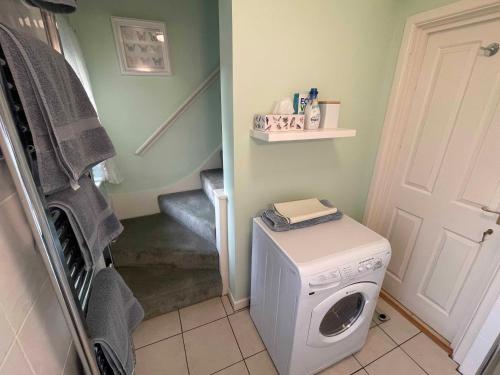 a laundry room with a washing machine and a staircase at Walkers Retreat with garden and views in Holne