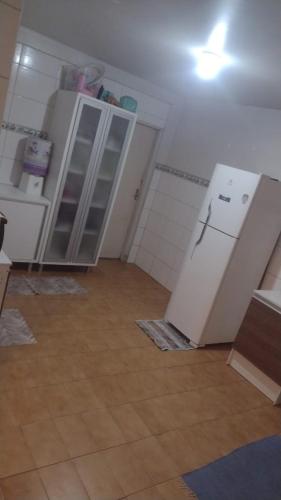 una cucina con mobili bianchi e un frigorifero di casa Magalhães a Laguna