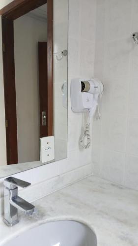 a bathroom with a sink and a hair dryer on the wall at HOTEL CAMPO ALEGRE in Campo Alegre