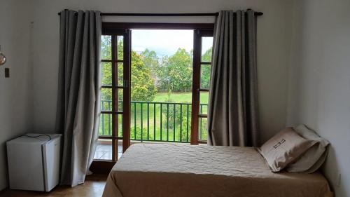een slaapkamer met een bed en een groot raam bij HOTEL CAMPO ALEGRE in Campo Alegre