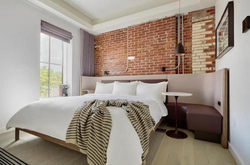 a bedroom with a white bed and a brick wall at Lark Hotels 907 Main in Cambridge