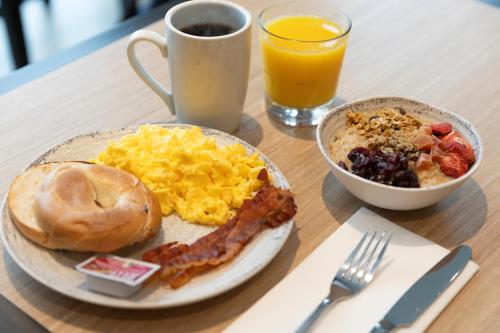 a plate of breakfast food with eggs bacon and a cup of orange juice at Hampton Inn La Crosse/Onalaska in Onalaska