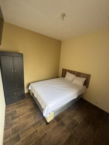 a bedroom with a white bed and a cabinet at Hotel El Alero in Chimaltenango