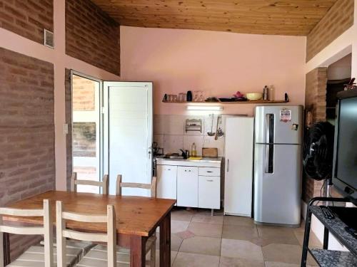 a kitchen with a wooden table and a refrigerator at Cabañas Las Pasionarias in Tanti