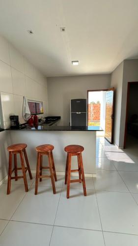 a kitchen with two wooden stools and a counter at Casa de praia Cleo in Luis Correia
