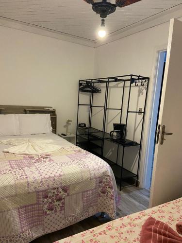 a bedroom with two beds and a shelf at Mara e Jorge Suites Beira Mar in Cananéia