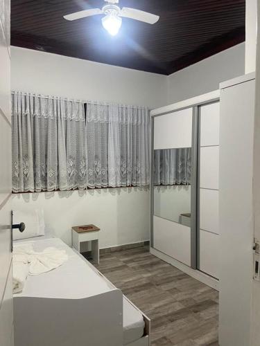 a bedroom with a white bed and a window at Mara e Jorge Suites Beira Mar in Cananéia