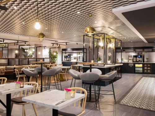 een restaurant met tafels en stoelen en een bar bij Novotel Den Haag City Centre in Den Haag
