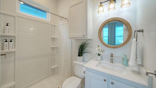 een badkamer met een toilet, een wastafel en een spiegel bij 2 Homes Sleeps 22 2 Private Pools Firepit Steps to Beach Boardwalk Access in Mustang Beach