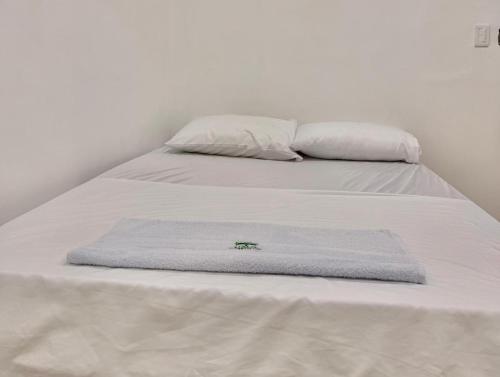 zwei Betten mit weißen Laken und einem Handtuch darauf in der Unterkunft Haití Hotel B in Tumaco