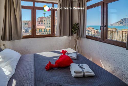 a red stuffed animal sitting on a bed with towels at La Torretta dei Merli Studio with Unique Views in Vernazza