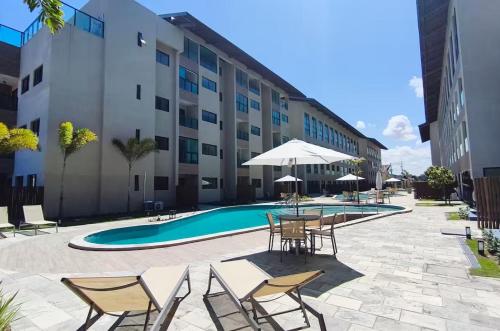 eine Terrasse mit Tischen und Stühlen und einem Pool in der Unterkunft Apartamento na Praia dos Carneiros a 250m do mar in Praia dos Carneiros