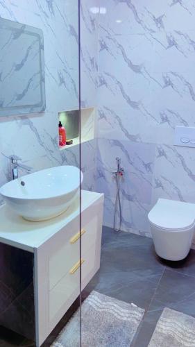 a bathroom with a white sink and a toilet at Yadal Home in Darou Rhamane