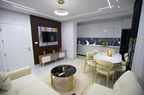 a living room with a table and a kitchen at Golden Apartment Korce in Korçë
