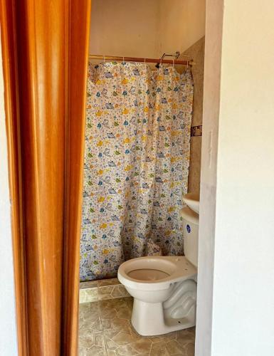 a bathroom with a toilet and a shower curtain at Ecohotel Los Cedros in Cocorná
