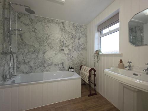 a bathroom with a tub and a sink at Outrake Cottage in Coniston
