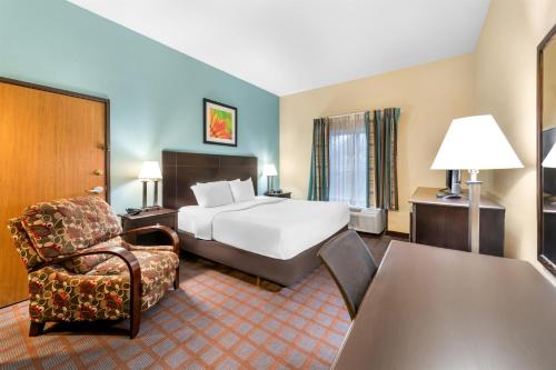 een hotelkamer met een bed en een stoel bij Red Lion Inn & Suites Blue Springs in Blue Springs