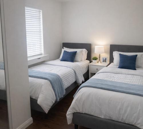 two beds with blue pillows in a bedroom at Irolo Guesthouse in Los Angeles