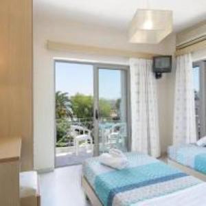 a bedroom with two beds and a window with a balcony at Villa Krini in Georgioupolis