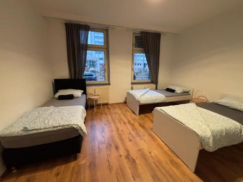 a room with three beds and two windows at Duisburg Flats 24 in Duisburg